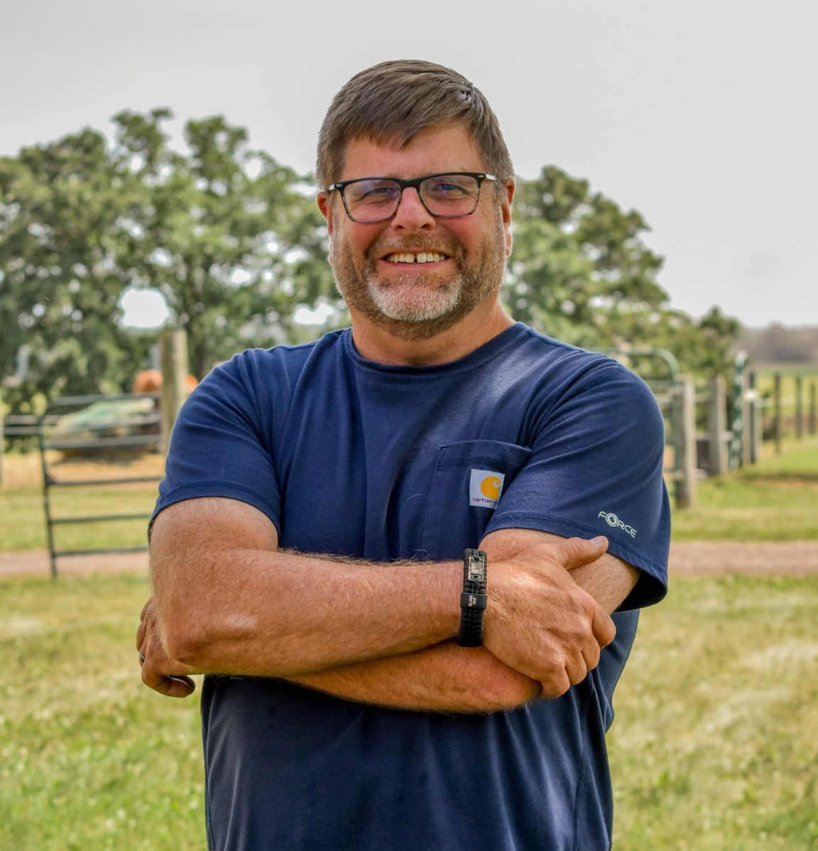 Jim Smale, arms folded and smiling, by the paddock gate at Huckberry Farm
